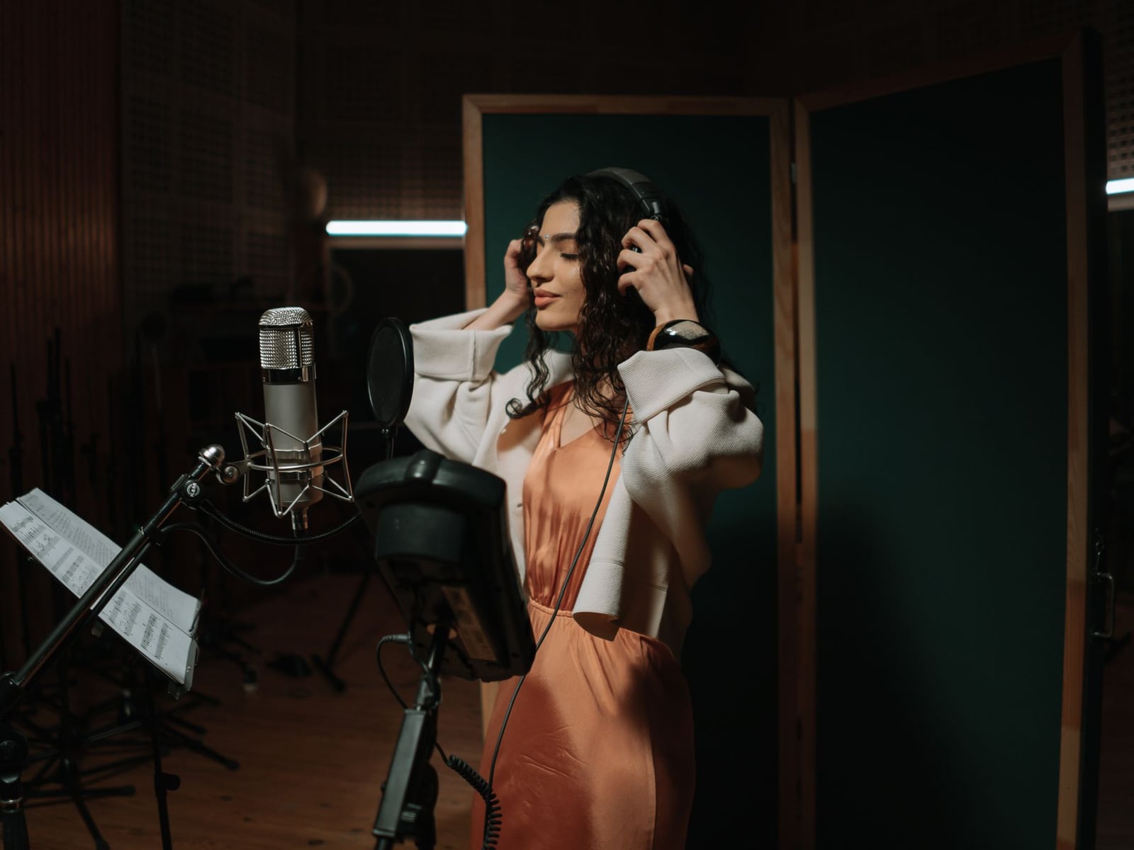 A singer during a recording session in a soundproof vocal booth with a professional microphone